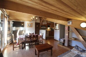 A wooden interior with a dining area, kitchen, and a staircase.