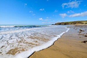 A beach with waves, a clear sky, and distant hills.