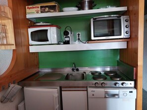 Una cocina compacta equipada con microondas, tostadora y estufa.