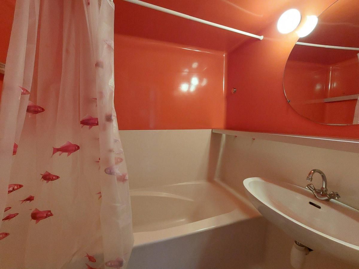 A bathroom with a bathtub, a sink, and a shower curtain with fish patterns.