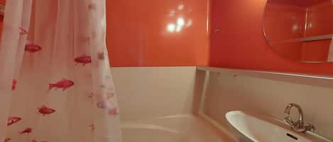 A bathroom with a bathtub, a sink, and a shower curtain with fish patterns.