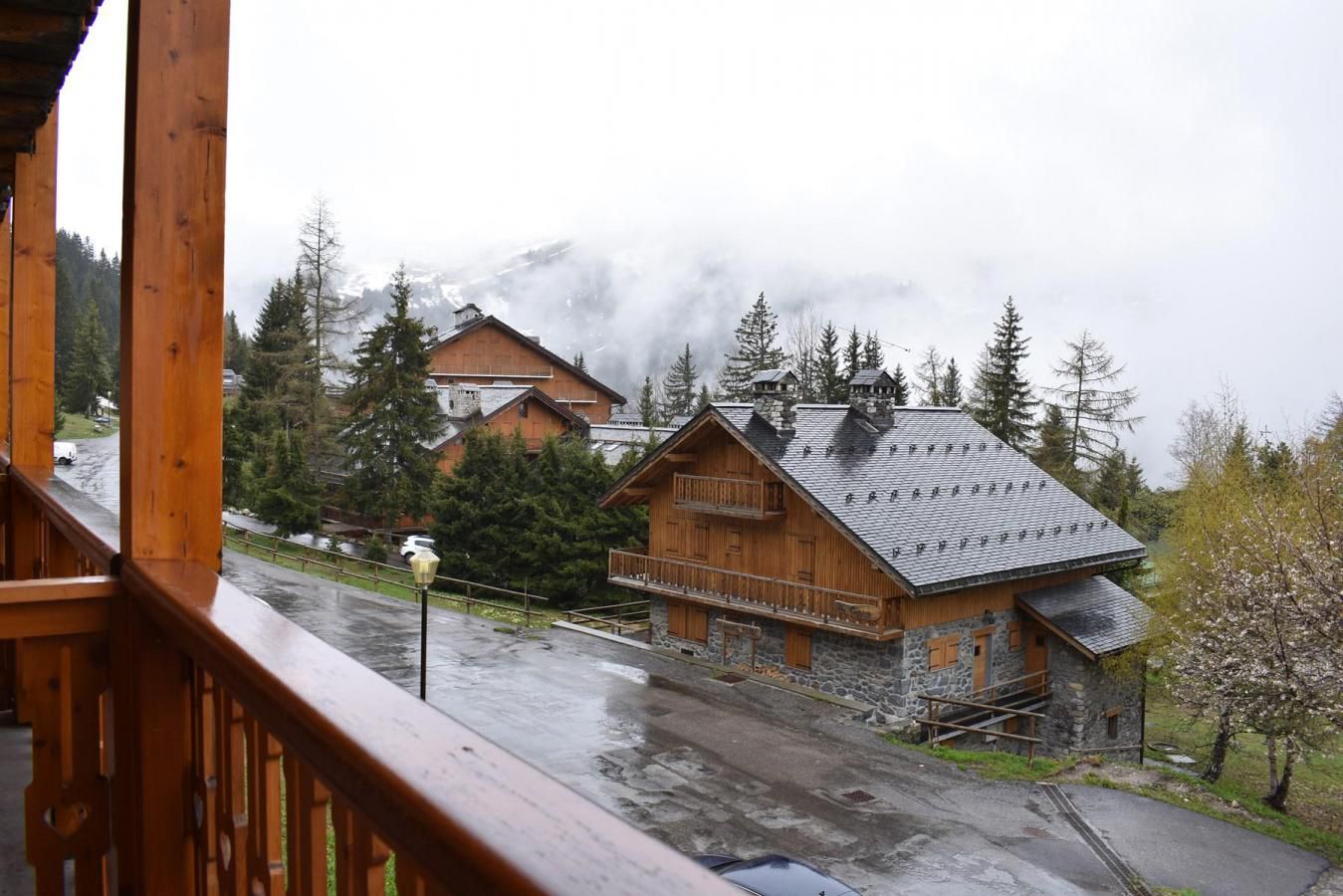 Un chalet en bois, avec des fondations en pierre, un balcon et une vue sur la montagne.