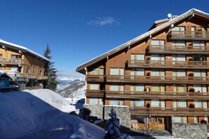 A multi-story hotel with balconies, a stone facade, and a view of snow-covered mountains. - 10m from ski slopes, 2nd floor, balcony, ski locker, 18m², Méribel-Mottaret (Méribel - Les Allues)