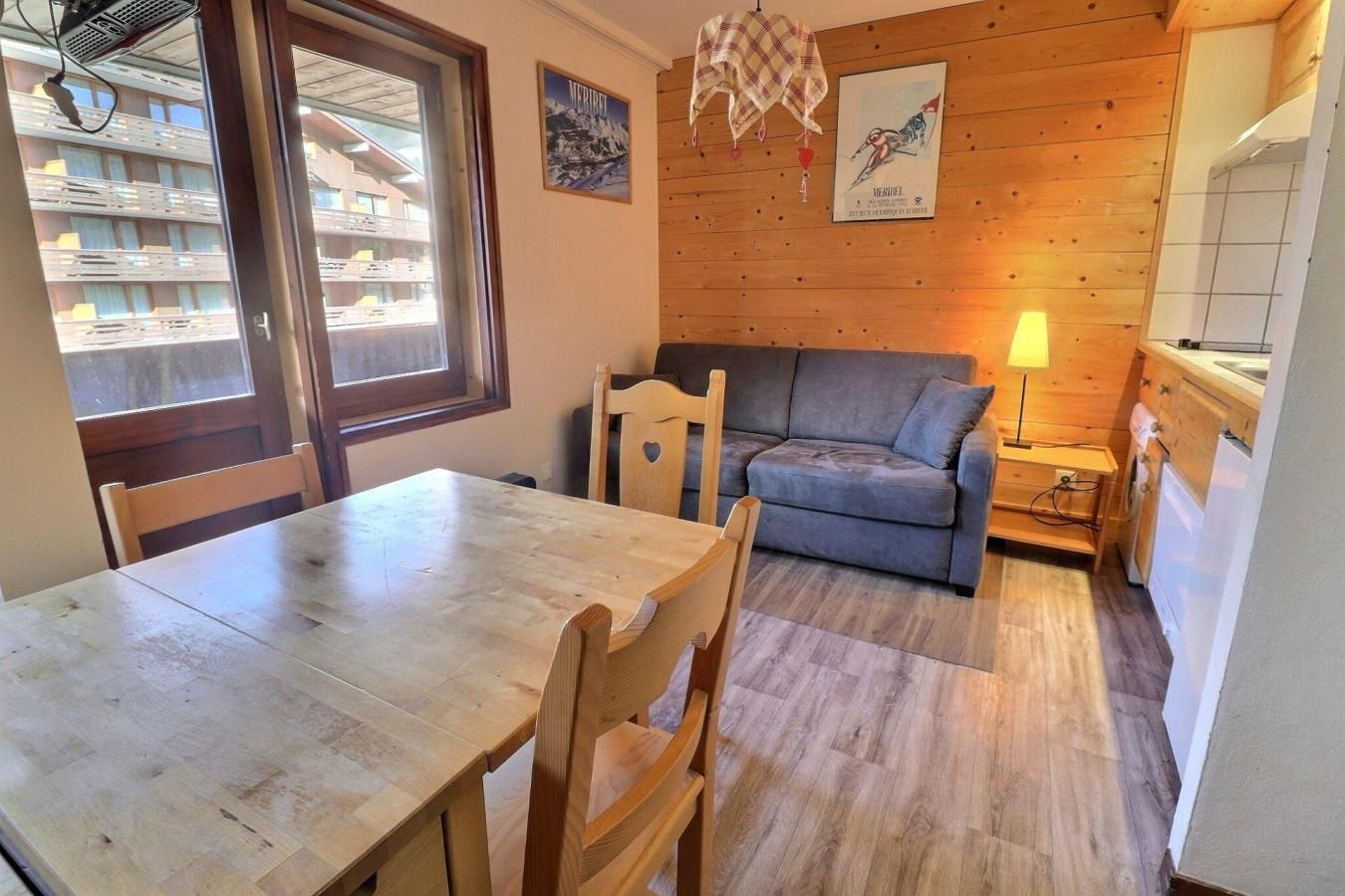 A cozy room with a wooden dining table, a sofa, and a kitchen area.