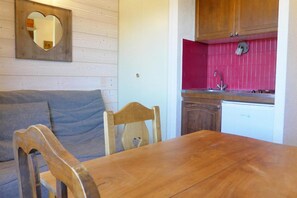 A compact kitchen with a red backsplash, wooden cabinets, and a white dishwasher.
