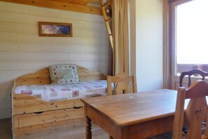 Cozy retreat with a wooden bed, chair, and table, featuring a quilted blanket and decorative pillow.