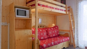 A wooden bunk bed with a built-in microwave shelf, a red patterned mattress, and a ladder. - 50m from ski slopes, Ground floor, 14m², Méribel-Mottaret (Méribel - Les Allues)