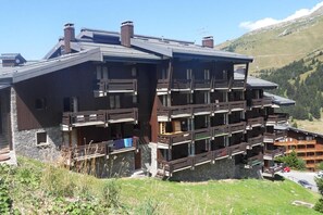 Un immeuble à plusieurs étages doté de balcons, situé dans une région montagneuse.