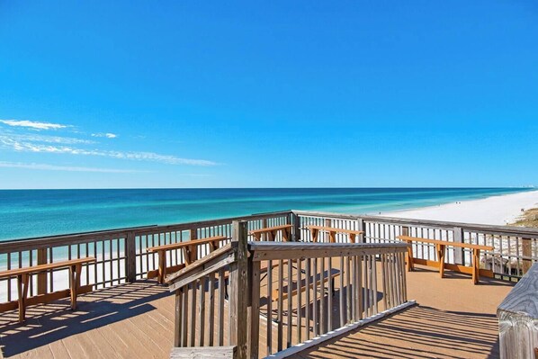 A wooden deck with benches overlooking a beach and ocean.