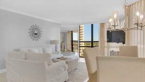 A modern hotel room with a white sofa set, a coffee table, and a TV mounted on the wall. - GULF VIEWS~Private beach! Comp beach chairs! (Miramar Beach)