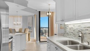 A modern kitchen with a large window, a dining area with a view, and a balcony. - GULF VIEWS~Private beach! Comp beach chairs! (Miramar Beach)