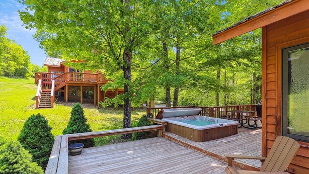 A wooden deck with a hot tub, seating, and a view of a cabin. - A spectacular space for every season-in winter a real skier's destination! (Canaan Valley)