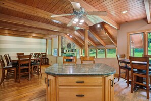 A spacious kitchen with wooden cabinets, a granite countertop, and a ceiling fan.
