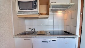 A compact kitchen with a microwave, toaster, and dishwasher. - 10m from ski slopes, 1st floor, balcony, 49m², Méribel-Mottaret (Méribel - Les Allues)