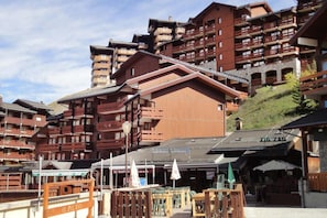 Un hotel de varios pisos con balcones de madera y un telesilla visible al fondo.