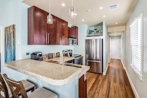 A modern kitchen with a central island, stainless steel appliances, and wooden cabinets.