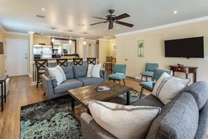 A living room with a sofa, chairs, a coffee table, and a TV.