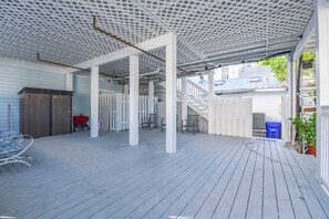 A covered outdoor area with a wooden deck, white railings, and a staircase leading to an upper level. - Sky Suites Retreat - Balcony Overlooking Duval (Key West)