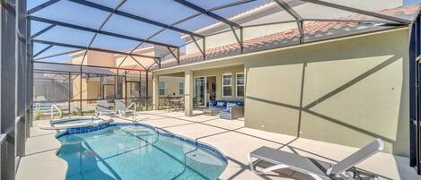 A covered outdoor swimming pool with lounge chairs and a patio area.