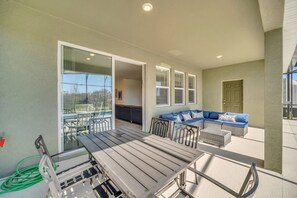 An outdoor patio area with a dining table, chairs, a sofa, and a small table.