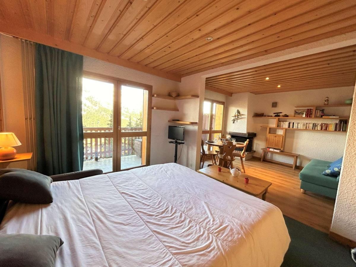 A bedroom with a large bed, a television, a dining area, and a balcony.