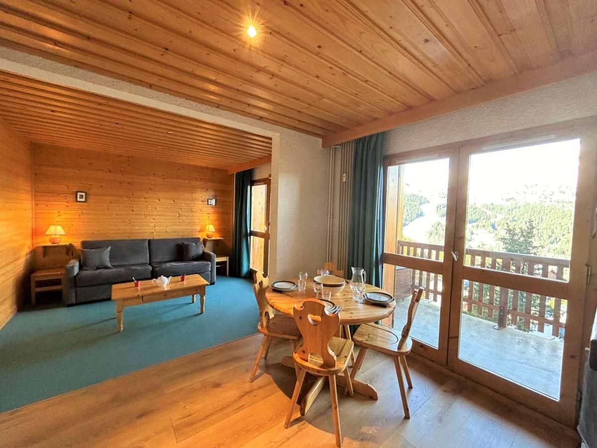 Un interior de madera con comedor, sofá y vistas amplias a través de grandes ventanales.