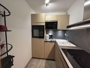 A compact kitchen with a built-in oven, microwave, and a modern sink. - 150m from ski slopes, 4th floor, balcony, fireplace or stove, ski locker, 39m², Méribel (Méribel - Les Allues)