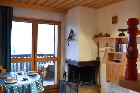 A cozy room with a fireplace, a dining table set for four, and a bookshelf.