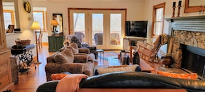 A cozy living room with a fireplace, a television, and a large window. - Red Roof Cottage in Holly Forest, Mountain View Home in the Sapphire Valley Resort (Jackson County)