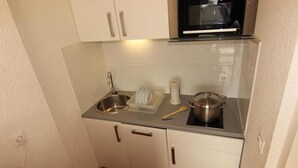 A compact kitchenette with a stainless steel sink, a microwave, and a stovetop. - 10m from ski slopes, 1st floor, balcony, ski locker, 21m², Val Thorens (Val Thorens)