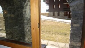 A room with stone pillars, a wooden door, and a view of a building outside. - 200m from shops, view ski slopes, terrace, ski locker, 27m², Valmorel (Valmorel)