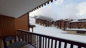 Un balcon donnant sur une montagne enneigée et une rangée de bâtiments.