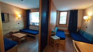 Une petite pièce comprenant un lit, une petite table, une chaise et un canapé.