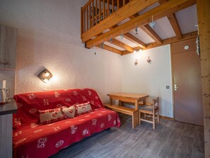 Une pièce chaleureuse avec un canapé rouge, une table en bois et un banc.