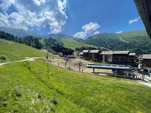 A ski resort with a chairlift, buildings, and a mountainous backdrop.