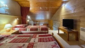 Un dormitorio acogedor con dos camas, un televisor y techo de madera.