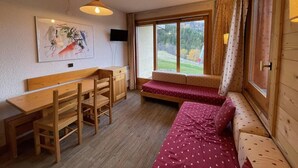 A cozy room with a wooden bench, a small table, and a bed with a red polka dot bedspread. - 200m from ski slopes, floor -1, view ski slopes, terrace, tv, ski locker, 21m², Valmorel (Valmorel)