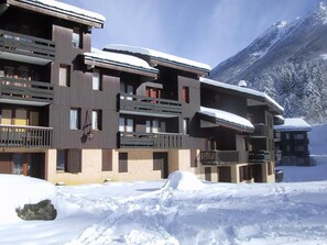 A multi-story hotel with balconies, set against a snowy mountain backdrop. - Ski-in/ski-out & foot of the slopes, 1st floor, view building, balcony, tv, ski locker, 26m² (Valmorel)
