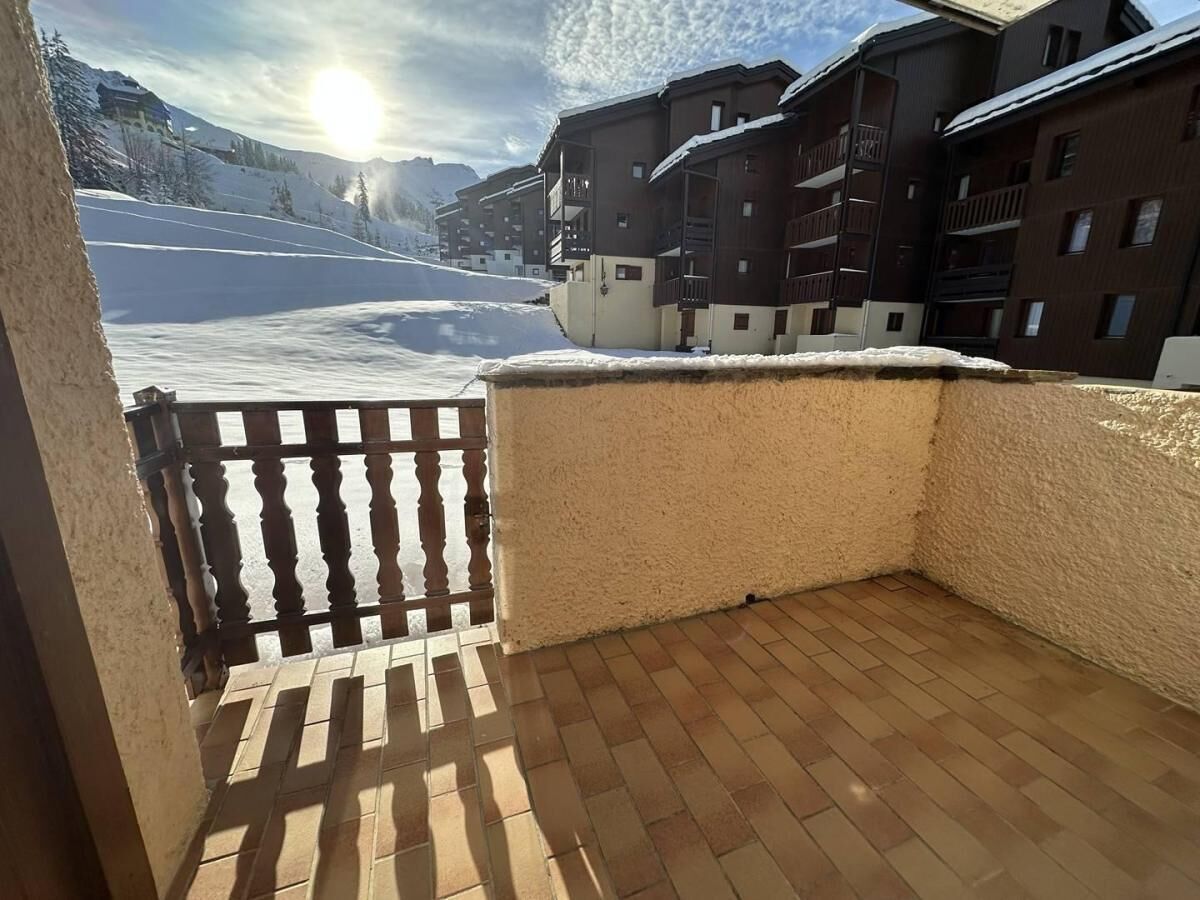 A balcony with a view of a snow-covered slope and buildings.