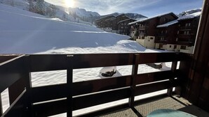 A snow-covered mountain landscape with a wooden balcony overlooking a ski slope.