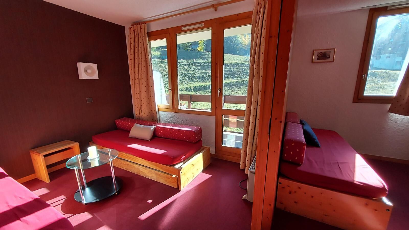 A cozy room with a bed, a small table, and a window with curtains.