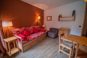 A cozy room with a wooden sofa, a small chair, a wooden table, and a lamp.