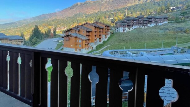 Un complejo turístico de montaña con varias construcciones, cielo despejado y vistas de las colinas circundantes.