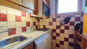 Una cocina compacta con fregadero, estufa y microondas.