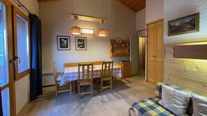 Una habitación acogedora con techo de madera, una mesa de comedor con sillas, un sofá y un cuadro en la pared.