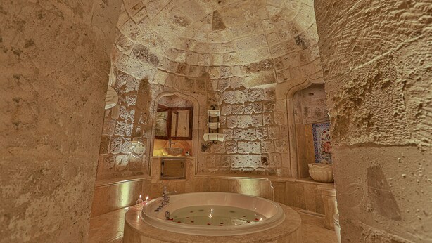 A stone-walled bathroom with a bathtub, a sink, and a mirror.