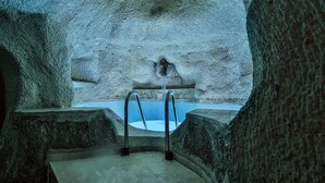 An ice bath with metal ladders, surrounded by stone walls.