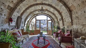 A room with a stone arched ceiling, a patterned rug, a sofa, a table, and chairs.
