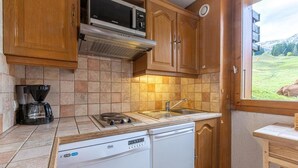Una cucina compatta con mobili in legno, forno a microonde integrato, macchina da caffè ed elettrodomestici inclusi.