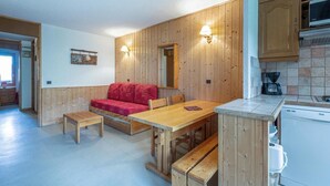 Una cucina accogliente con mobili in legno, un divano rosso e un tavolo da pranzo con panche.